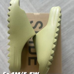 A pair of pale green Resin Yeezy Slides displayed on top of their shoebox, labeled with sizes and prices.