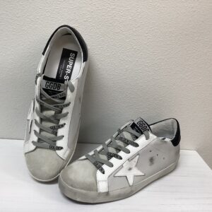 A pair of worn white golden goose sneakers with metallic laces and a star motif, displayed against a white background.