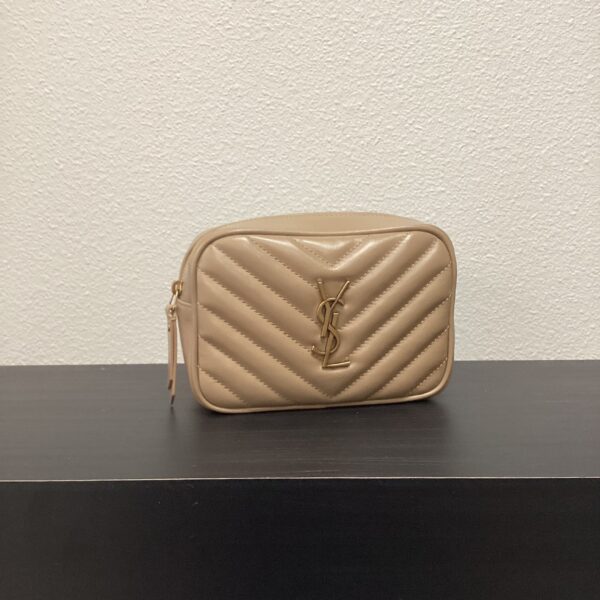 A beige quilted leather YSL 2 Way Belt Bag with a gold logo, placed on a black surface against a white wall.