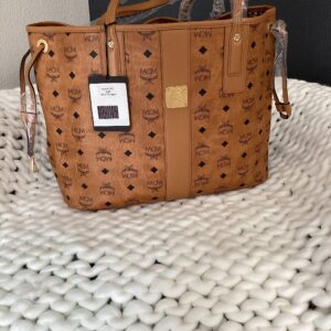 Brown MCM Shopper with logo pattern, placed on a white textured surface.
