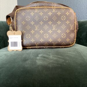 A Louis Vuitton crossbody bag with a classic monogram design, placed on a green velvet chair, featuring a visible barcode tag.