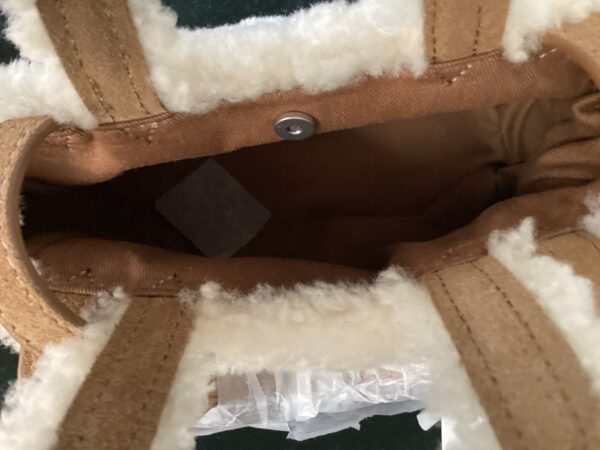 Close-up of a UGG X Telfar Bag's inside pocket, with the lining visible and a snap button closure.