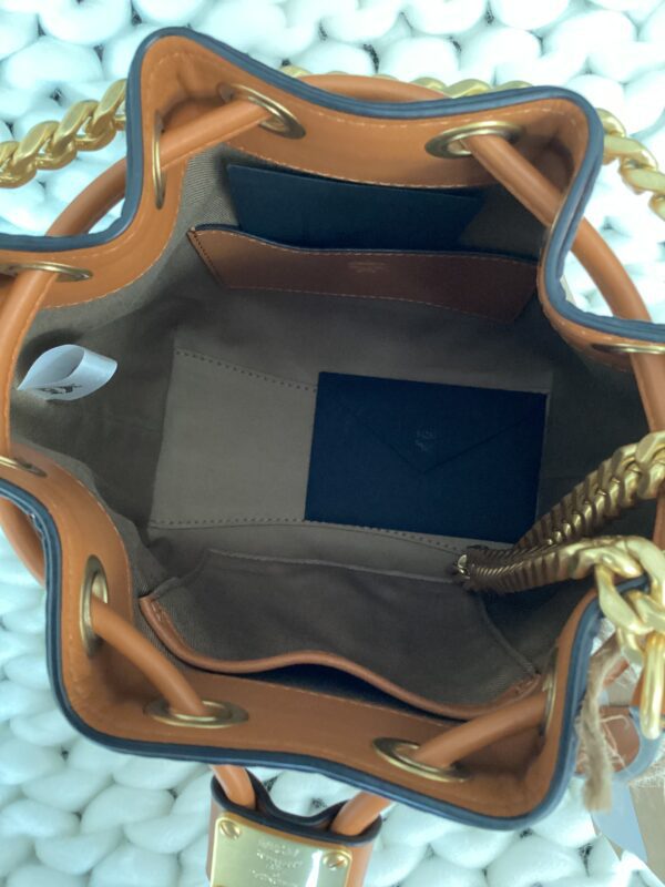 Interior view of an open, MCM Bucket Bag with a brown interior, showing a small blue envelope inside. the bag features gold chain handles and a visible padlock.