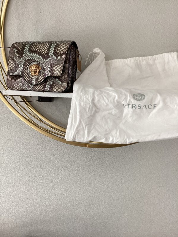 A YSL Bucket Bag resting on a circular shelf, partially covered by a white dust bag with the YSL logo.