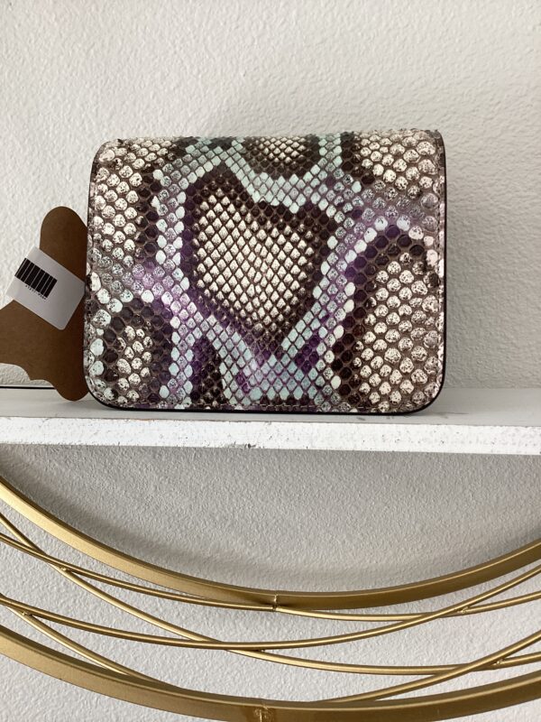 YSL Bucket Bag with geometric patterns on a white shelf above golden curved metal decor.