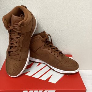 A pair of brown Nike Dunk High high-top sneakers displayed on a Nike Dunk High shoebox against a white background.