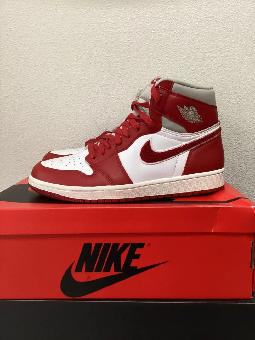 Red and white W Jordan Retro 1 sneaker displayed on top of its matching shoe box against a plain background.
