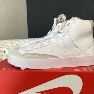 A white high-top sneaker displayed on a red Nike Dunk Low Retro shoebox.