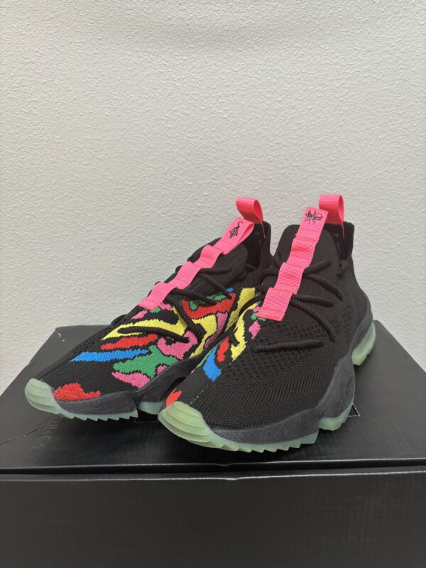 A pair of Sia Collective MACHE Multicolor sneakers with vibrant multicolored embroidery and pink pull tabs, displayed on a black box against a plain white background.