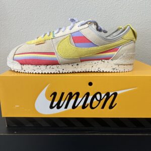 A Nike-Cortez UNION Lemon Frost with yellow and pastel stripes displayed on a shoebox.