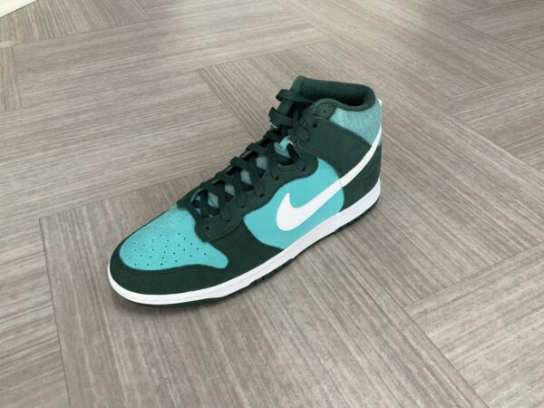 A teal and white High top Dunk SE (Athletic Club - Pro Green) sneaker on a wooden floor.