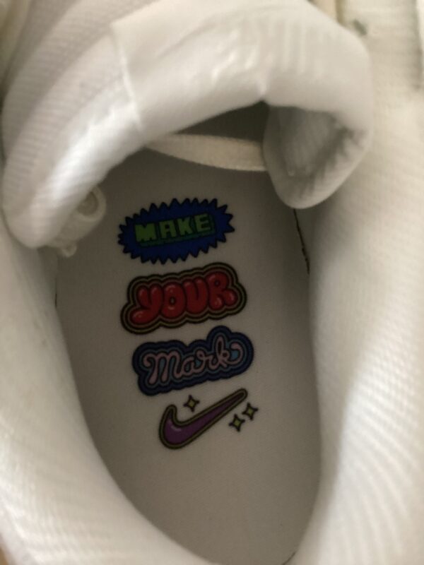 Close-up view of a white sneaker's inner sole showing colorful, inspirational "make your mark" slogan with a Nike Dunk Low logo.