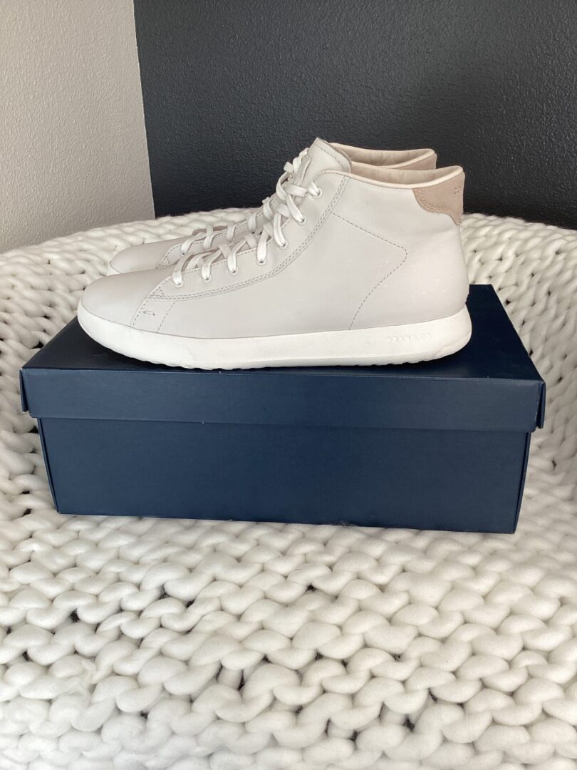 A pair of white Nike Huraches placed on a dark blue shoe box, which is set on a white textured rug.