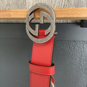 Gucci Light Blue Belt with a large circular silver buckle featuring an interlocking double g design, hung against a wood and gray background.