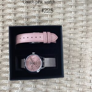 A pink coach watch displayed in an open black box, resting on a woven mat, with a price tag of $225 displayed at the top.
