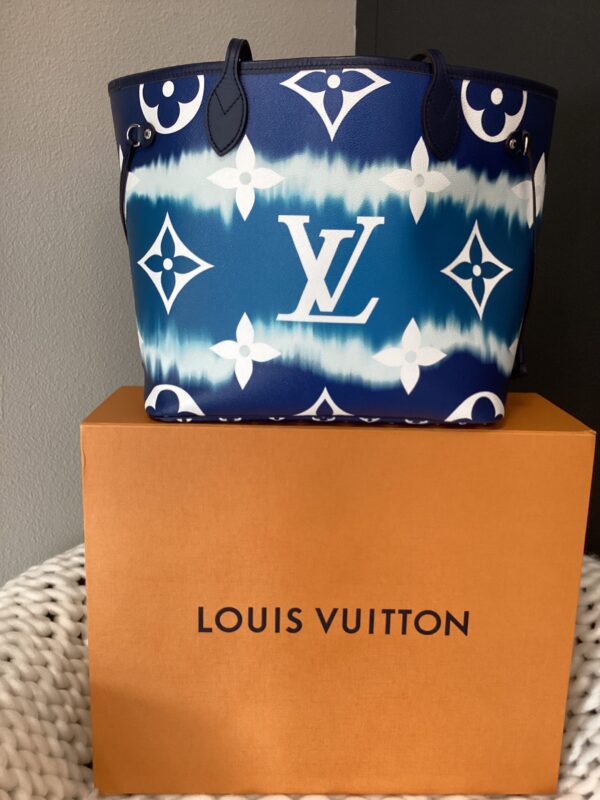 Blue and white LV MM Neverfull Bag with star and logo pattern, placed on a brown branded box against a gray background.
