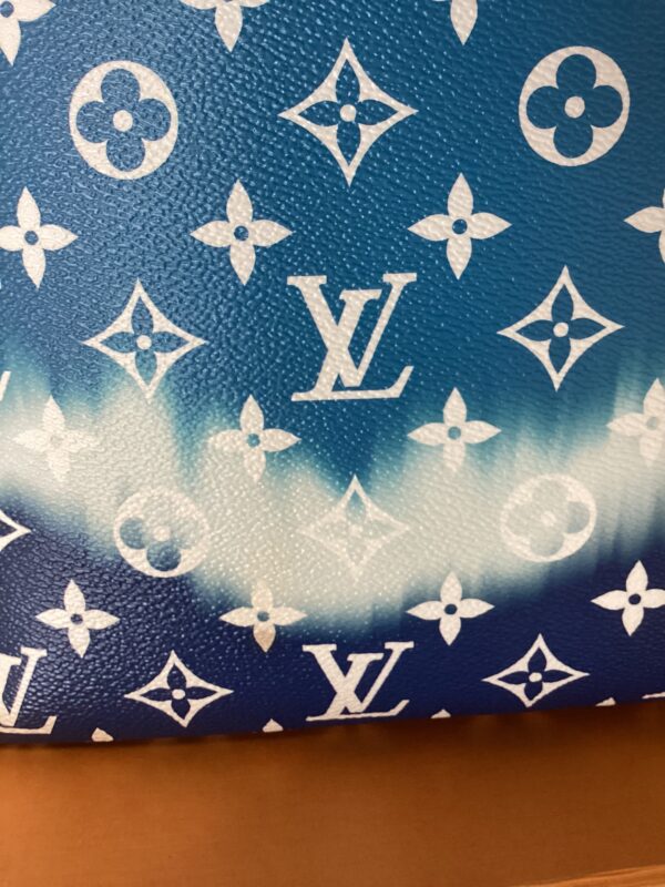 Close-up of a blue LV MM Neverfull Bag with iconic white logo and flower patterns.