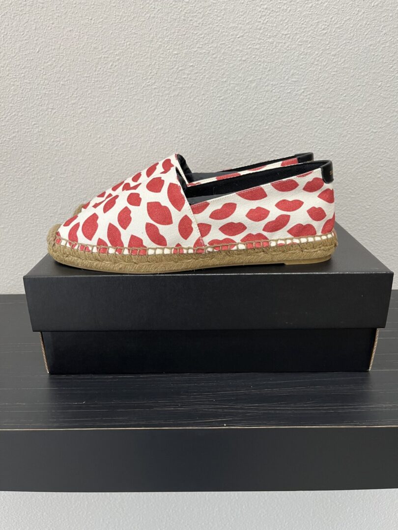 A red and white heart-patterned Nike Dunk Low Wheat/Sail Black shoe displayed on a black box against a gray background.
