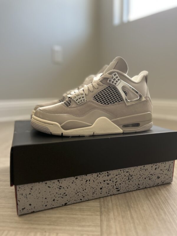 A single beige Jordan 4 Frozen Moment sneaker with mesh paneling displayed on a black and red speckled box in a well-lit room.