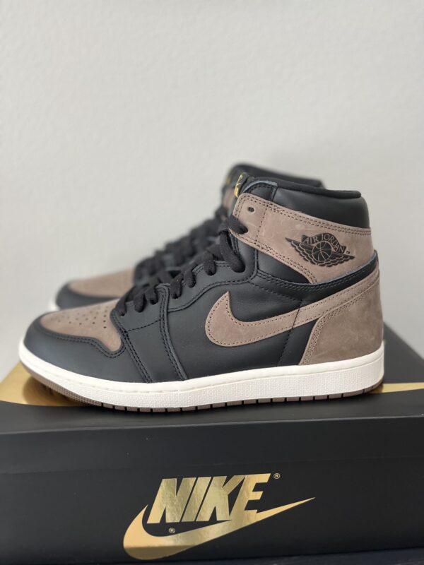 A pair of grey and brown Dunk Low Black sneakers placed on a black nike shoebox.