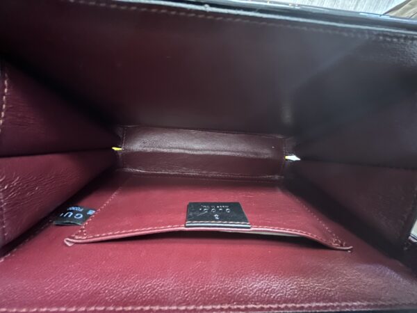 Interior view of an empty Gucci Black Handbag with a credit card partially visible.