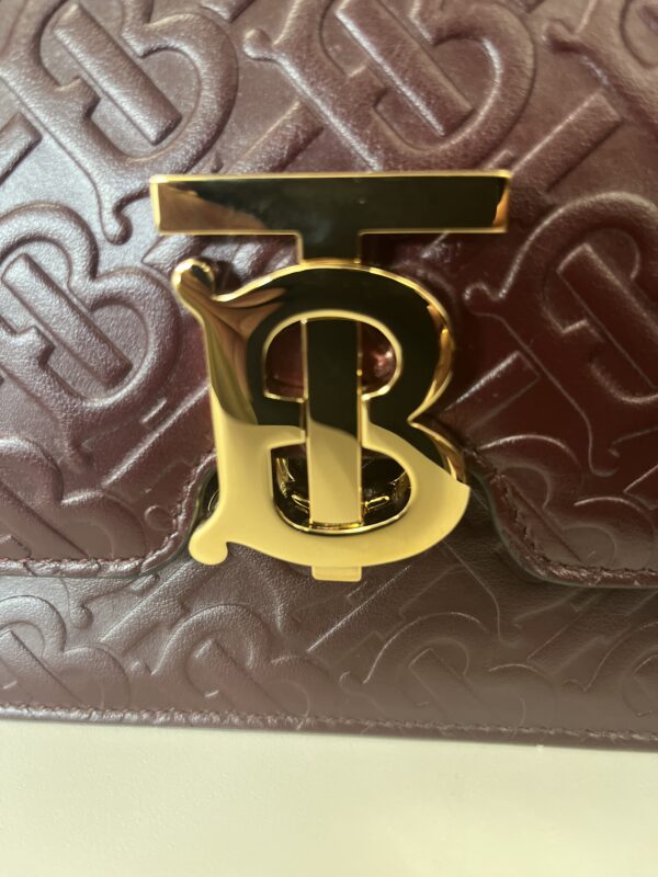 Close-up of a textured Gucci Black Handbag with a prominent gold 'b' logo clasp.